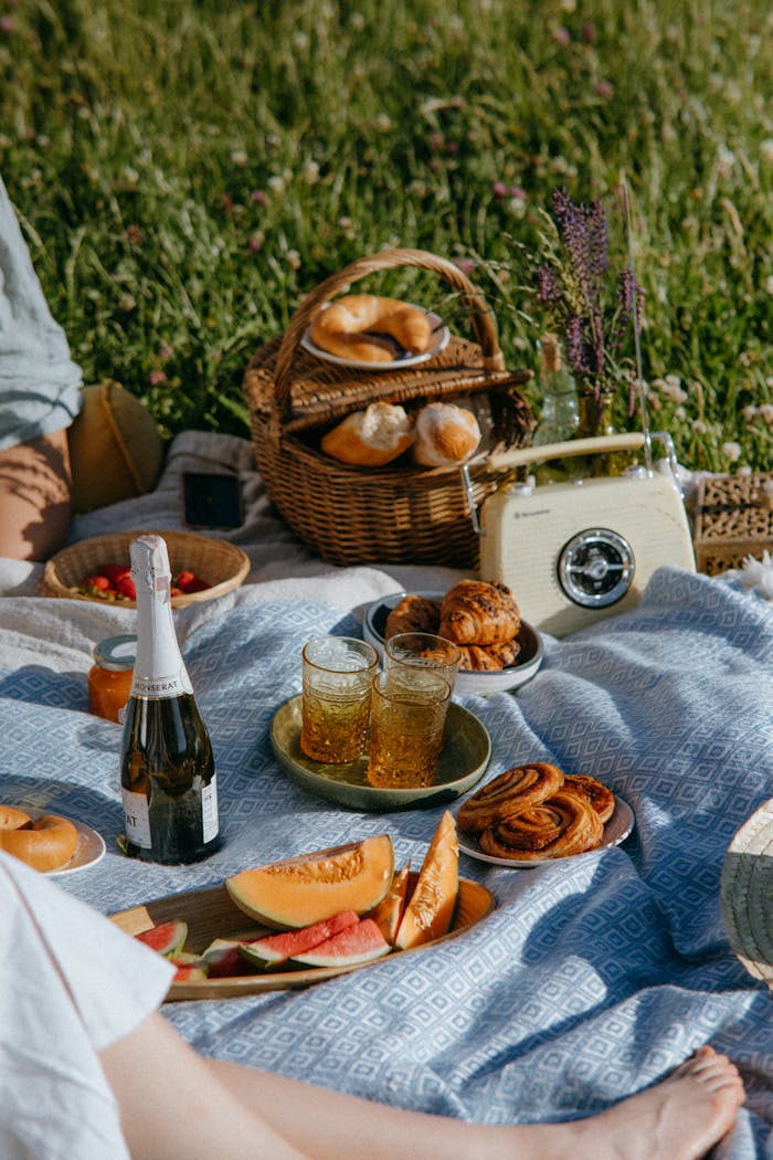Enjoy a summer picnic with wine, fresh pastries, and fruit under the sun on a scenic field.