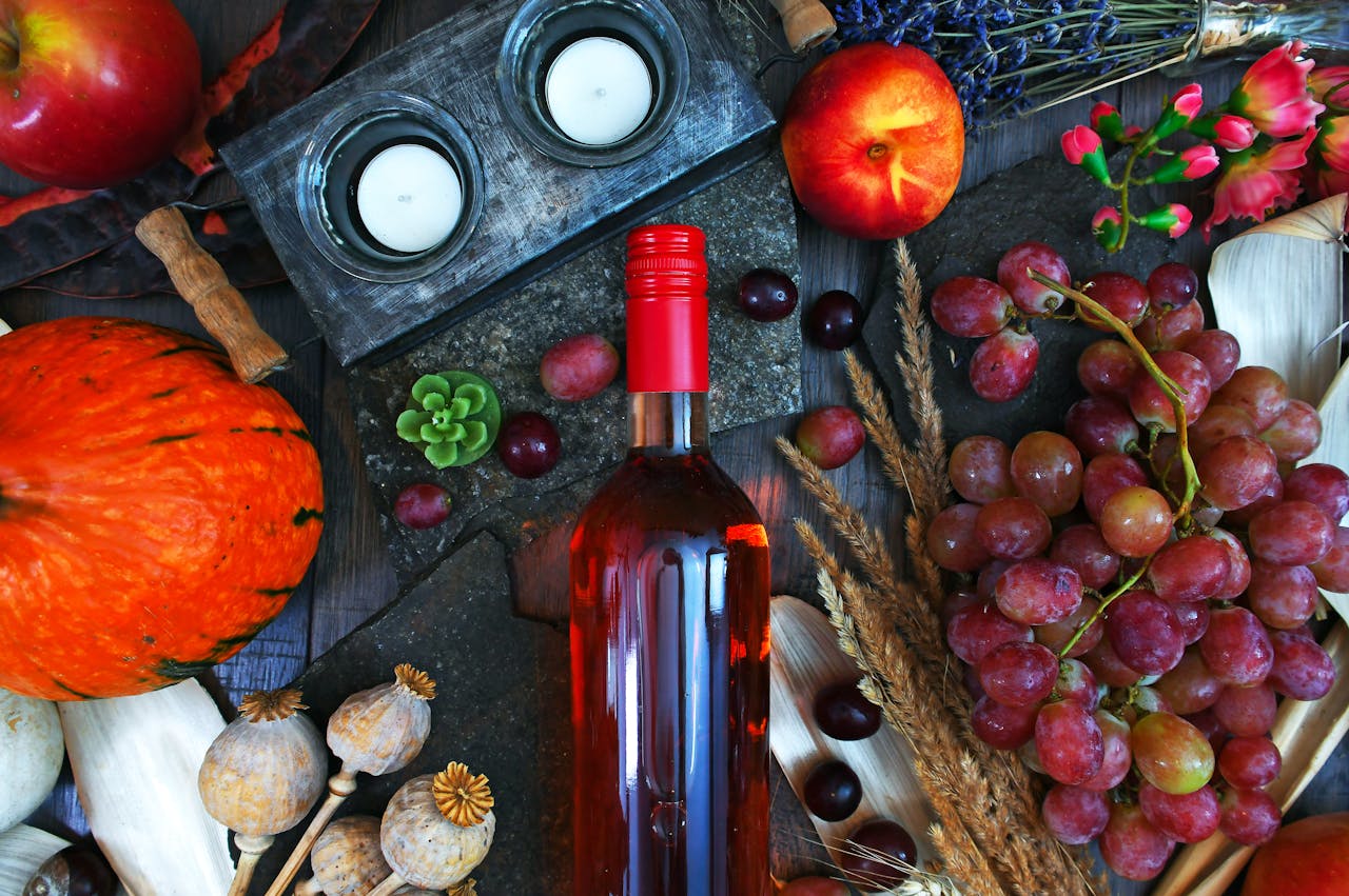 Vibrant autumn-themed still life featuring wine, fruits, and candles.